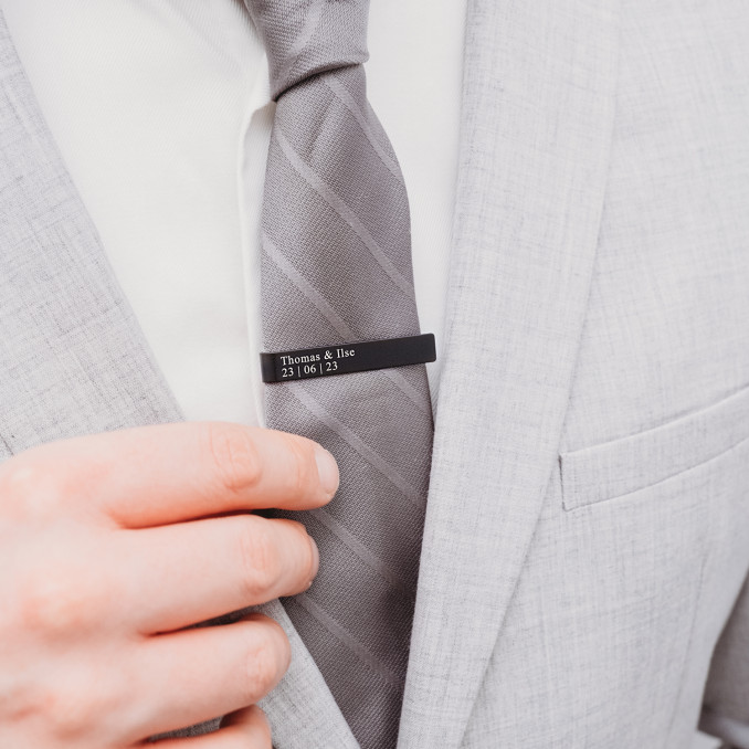 Zwarte dasspeld op grijze stropdas 