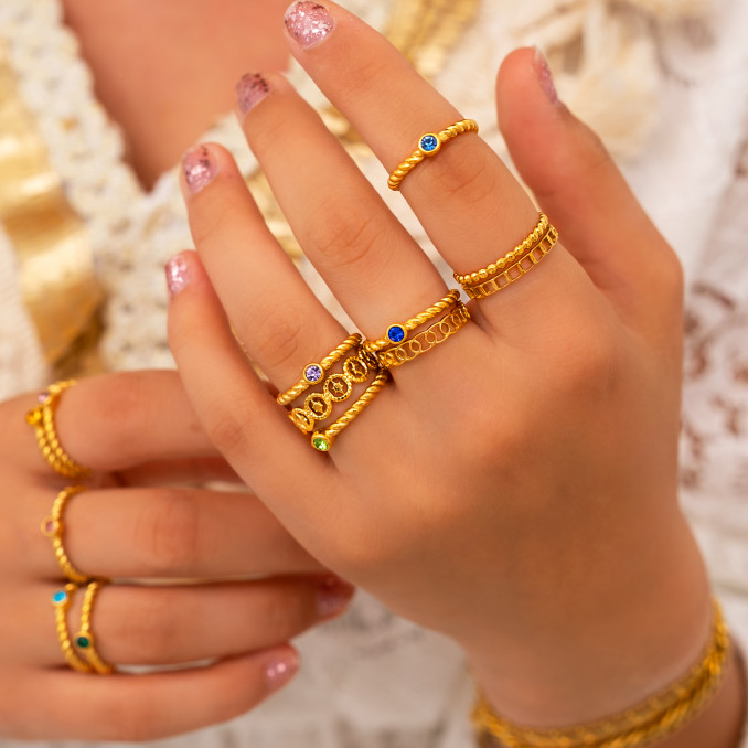 Vrouw draagt mix van geboortesteen ring en gouden rignen