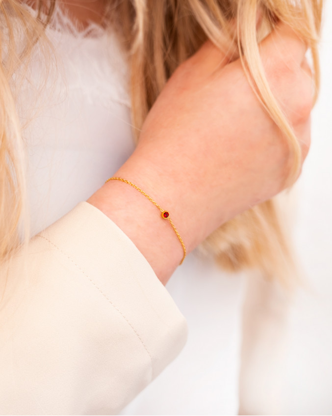 Meisje draagt geboortesteen armband met rood steentje