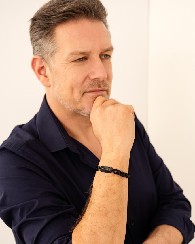 Man draagt zwarte tag armband met gravering