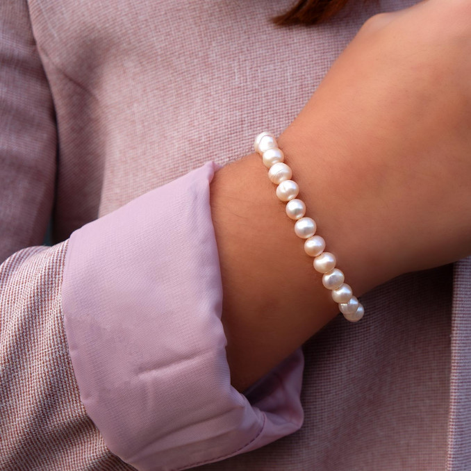 Vrouw draagt een nudekleurige parel armband om de pols