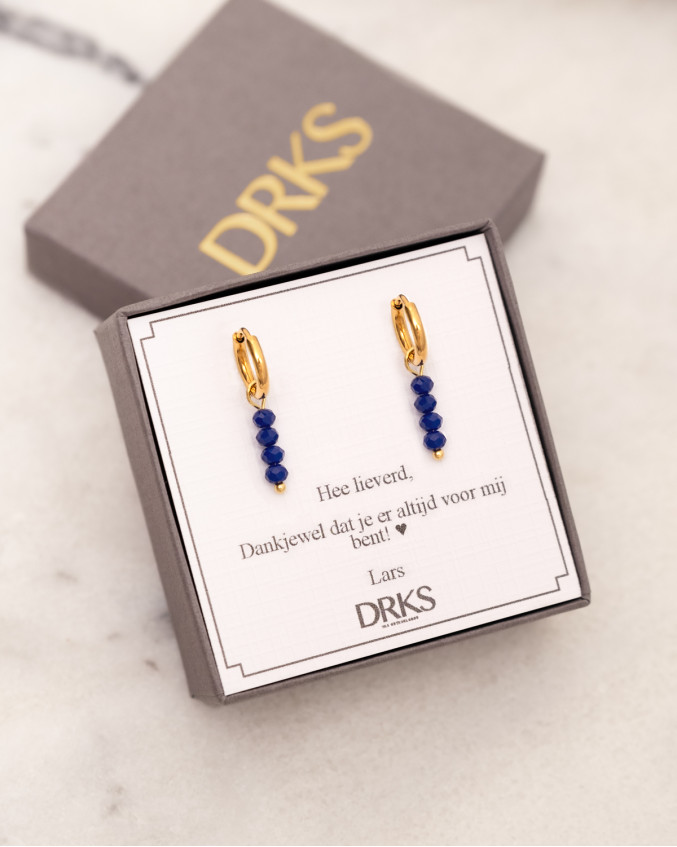 Gouden oorringetjes met blauwe details in DRKS sieradendoosje