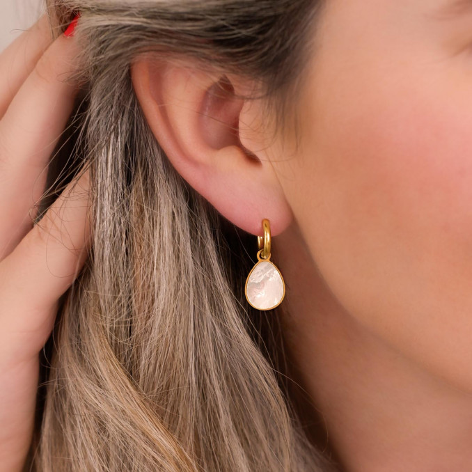 Vrouw draagt gouden sea shell oorbellen in oren