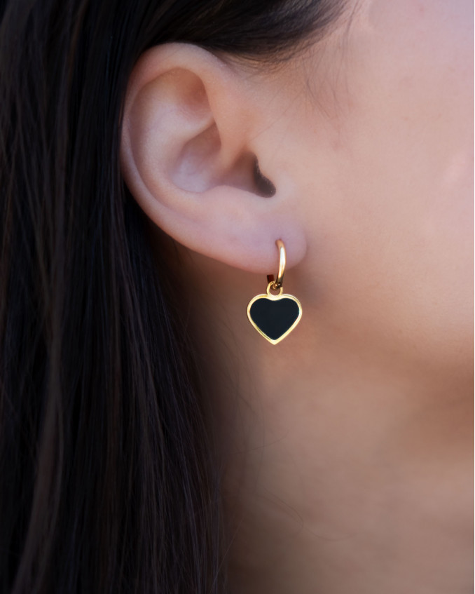 Het model draagt de goudkleurige oorbellen hart in het goud in haar oor