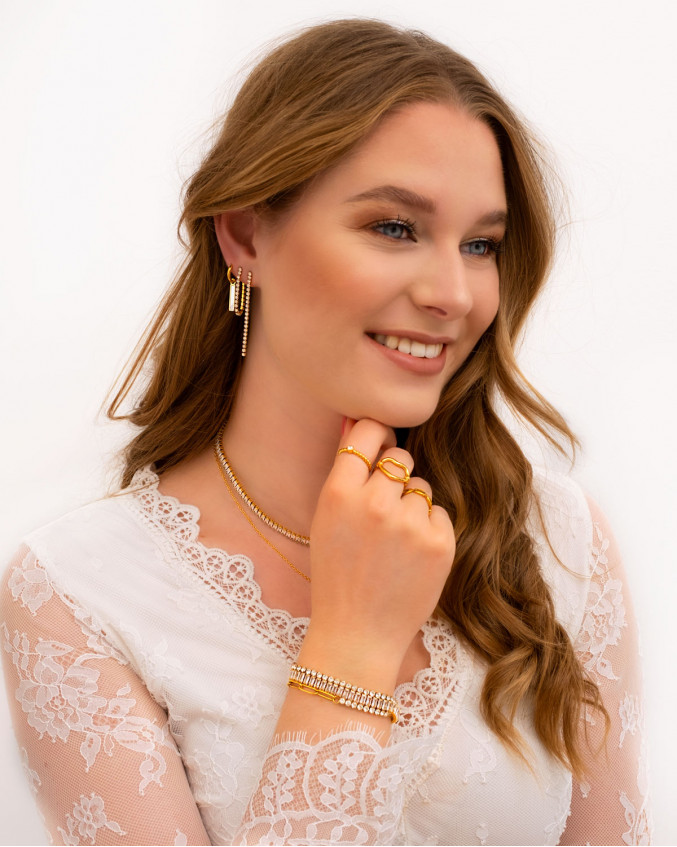 Model draagt gouden sieraden look met opal steentjes
