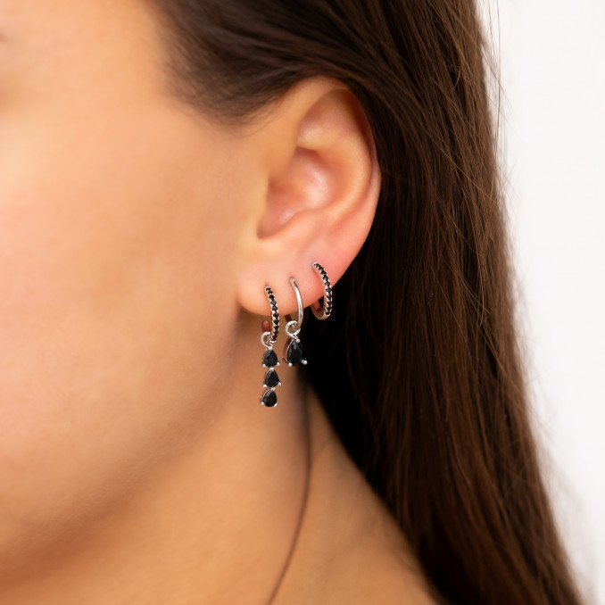Vrouw draagt Oorringetjes black drop in oor