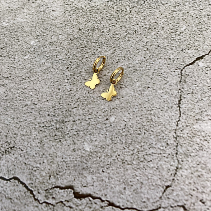 Gouden vlinder oorbellen op stenen ondergrond