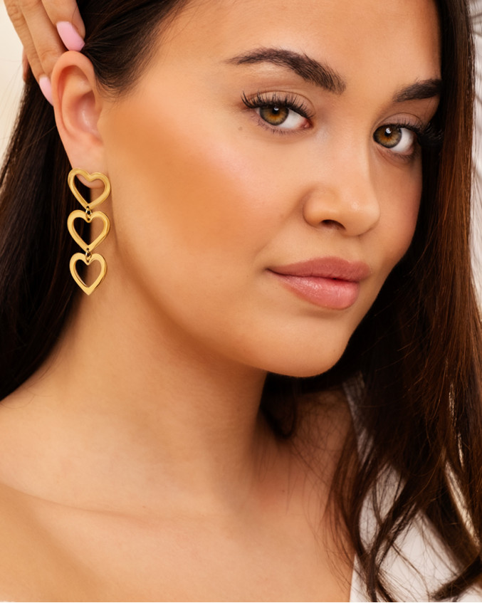 Model draagt gouden hartjes oorbellen
