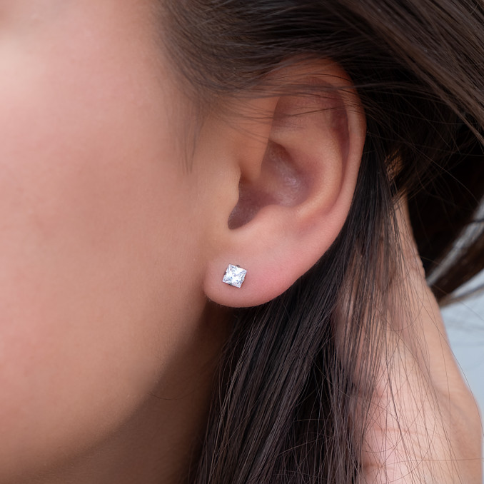 Vrouw draagt sparkle oorknopjes in het oor als minimalistische trend