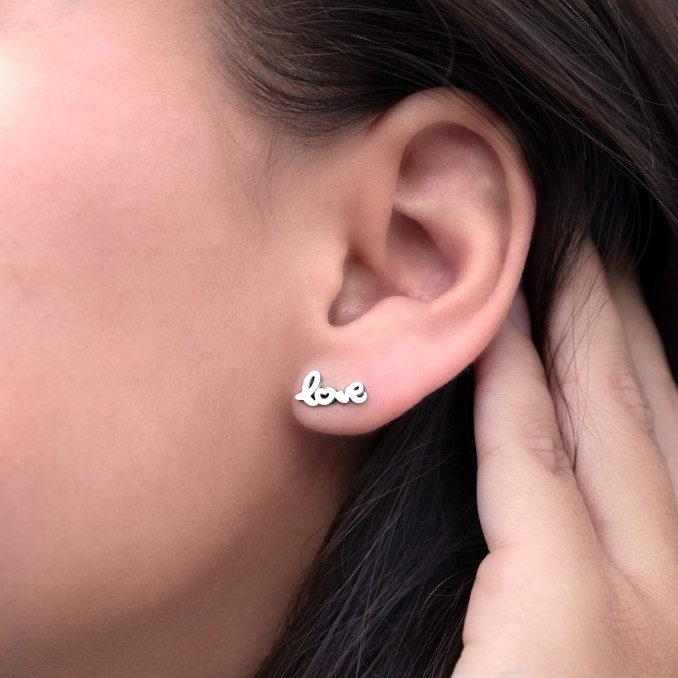 Zilveren stud oorbellen in het oor bij een vrouw met donker haar