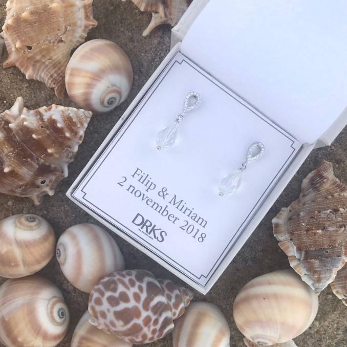 Zilveren klassieke oorbellen op een strand met schelpen