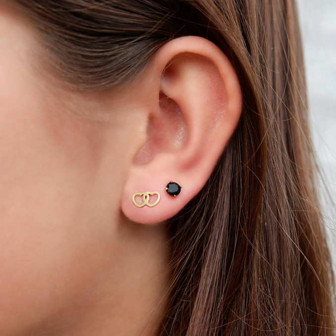 Gouden oorbellen met hartjes in het oor bij een jonge vrouw