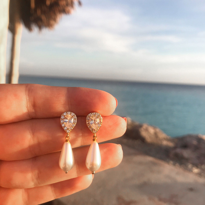 Mooie faux pearl oorbellen in de hand op een zonnige bestemming