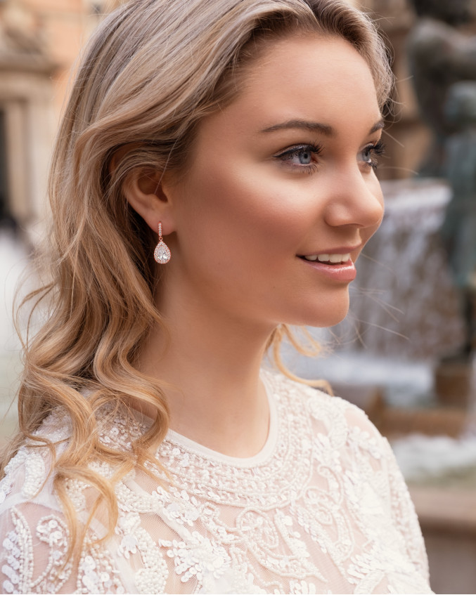 Model draagt rose gouden oorbellen voor de bruid
