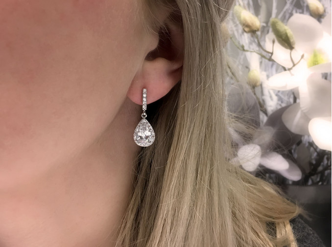 Vrouw met blonde haren draagt  zilveren sparkle oorbellen in het oor