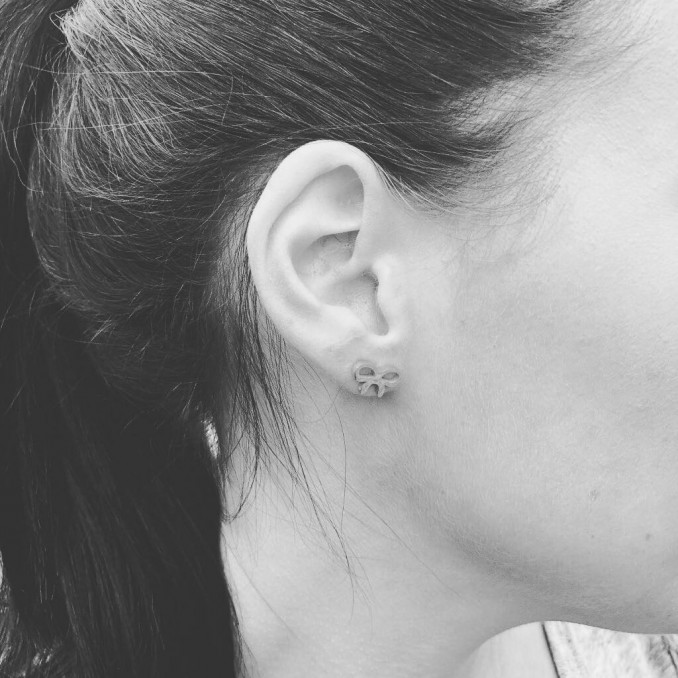 Vrouw draagt zilveren oorbellen met strikje