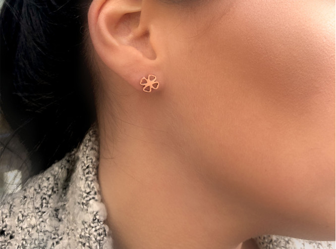 Vrouw draagt rose gouden klaver oorbellen in oor