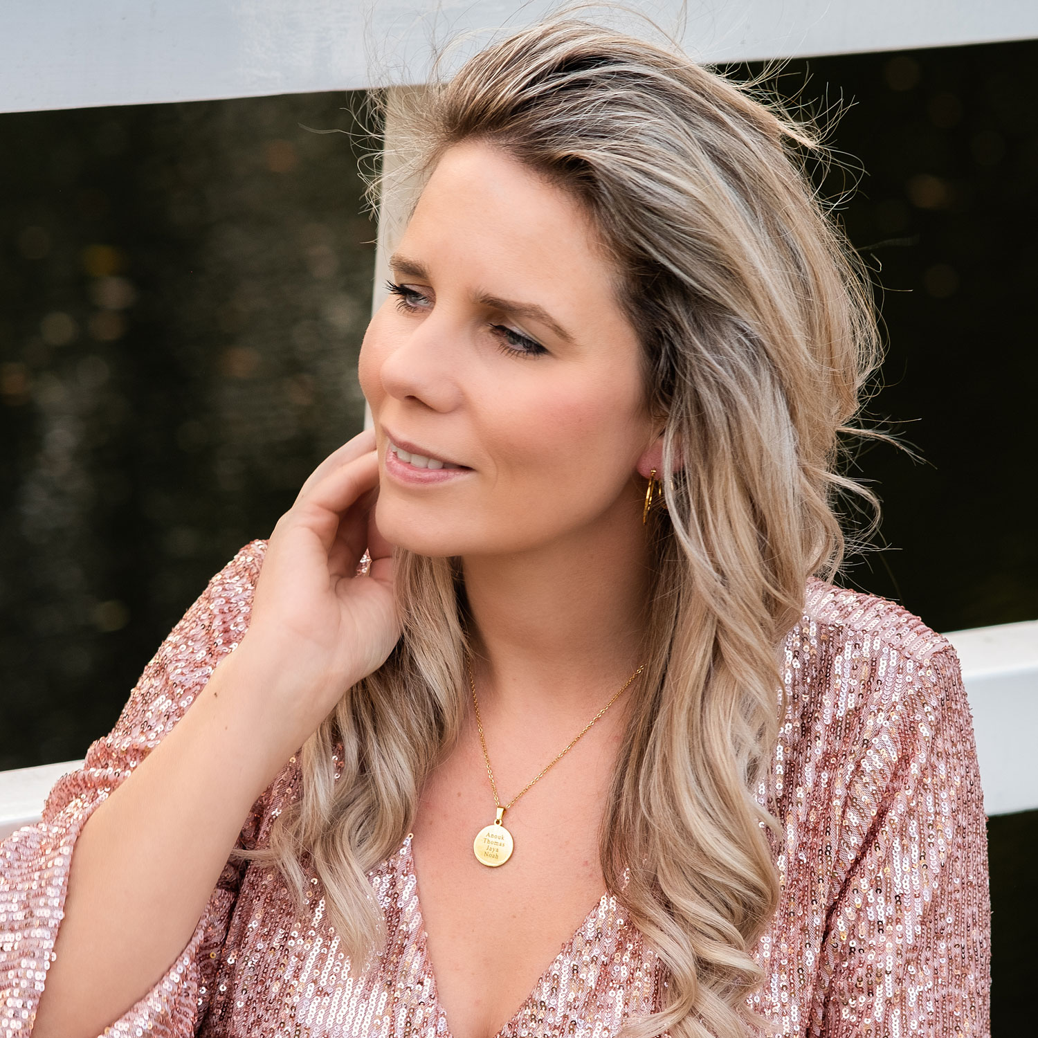 Blonde vrouw draagt gouden ketting met namen