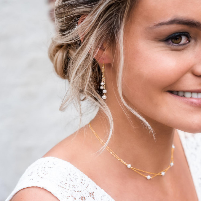 Bruid draagt een parelketting met matching oorbellen op haar grote dag