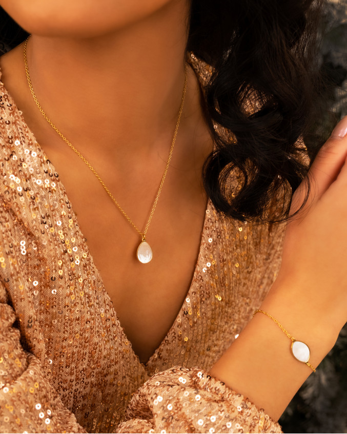Model draagt gouden sieraden parelmoer