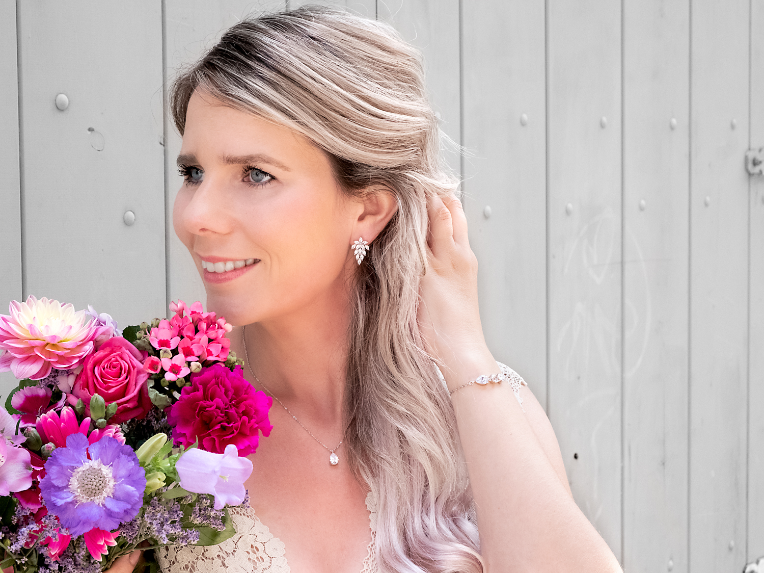 Bruid draagt sieraden in het zilver met bloemen en muur