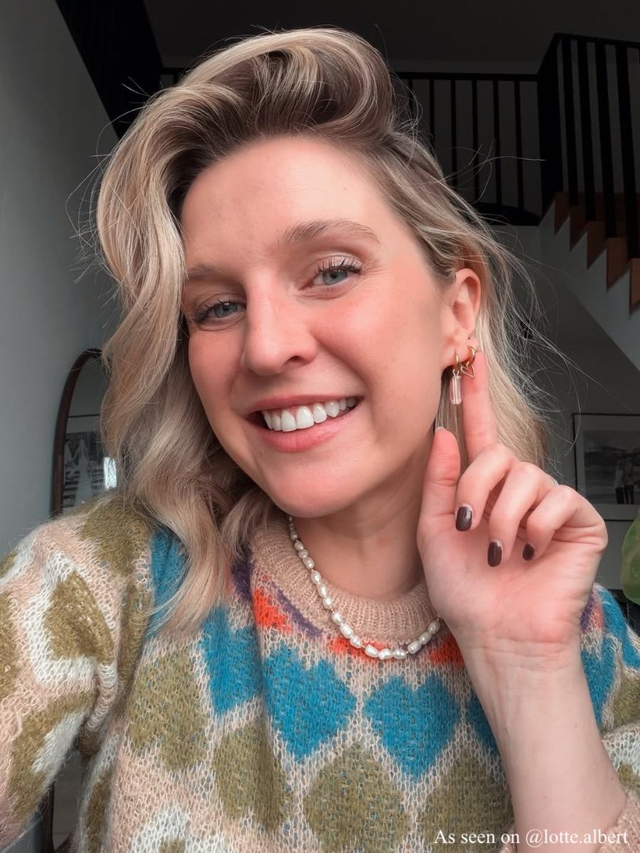 Influencer met gouden ketting en oorbellen met roze steentjes om