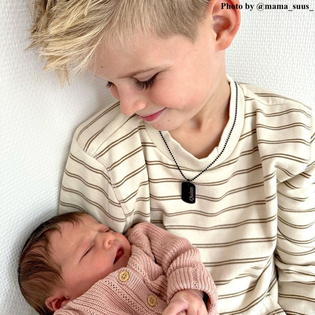blond jongetje met ketting om houdt baby vast