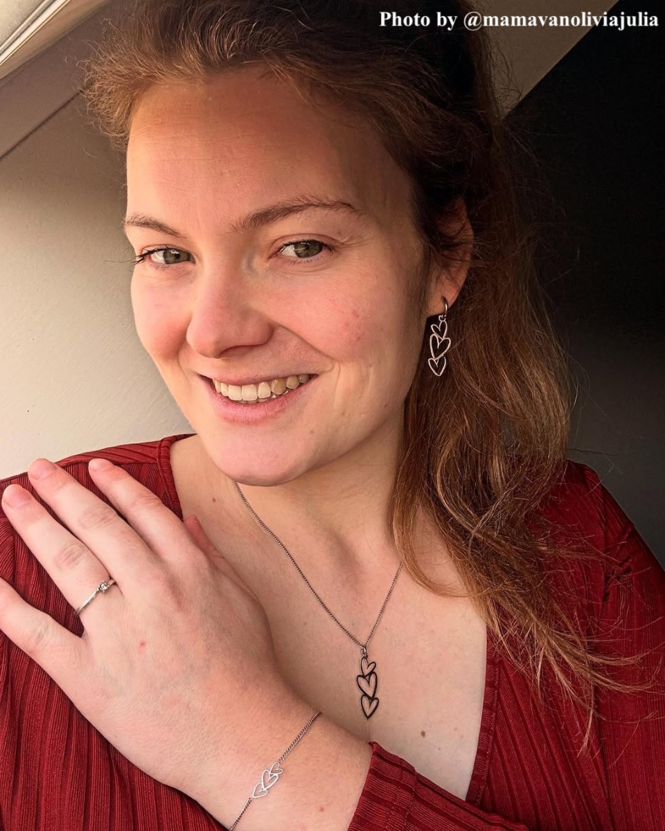 Model draagt zilveren triple heart oorbellen.