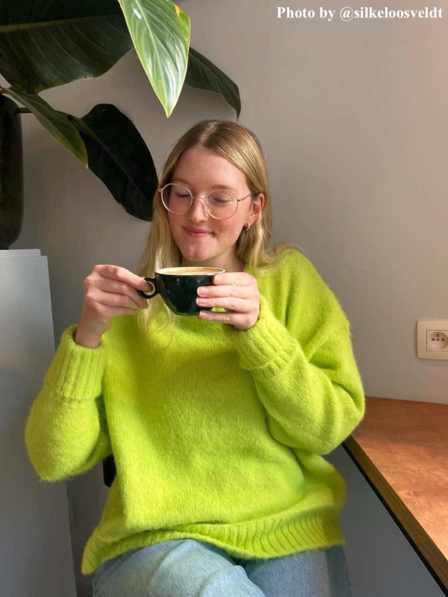 Influencer groene trui draagt DRKS oorbellen