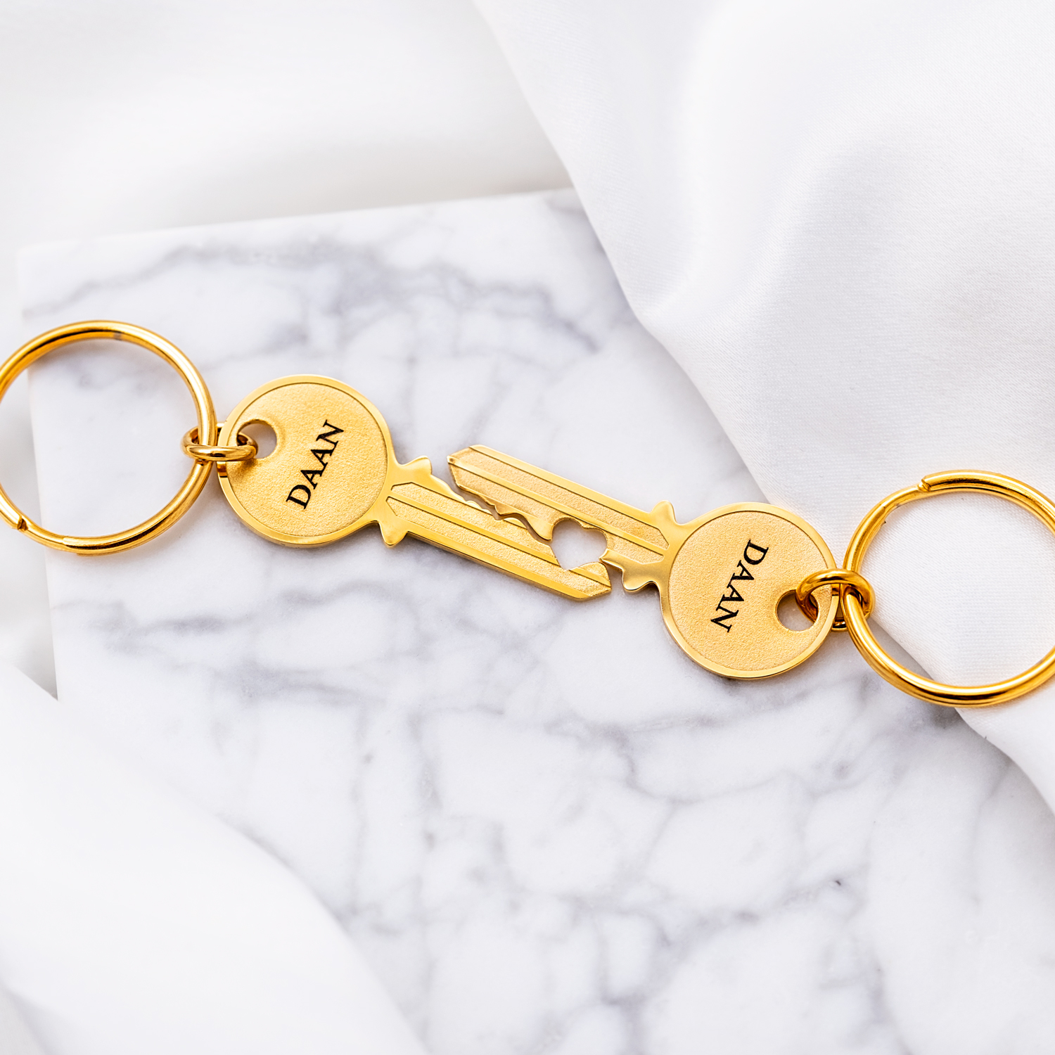 Gouden sleutelhangers met hartje op marmeren ondergrond