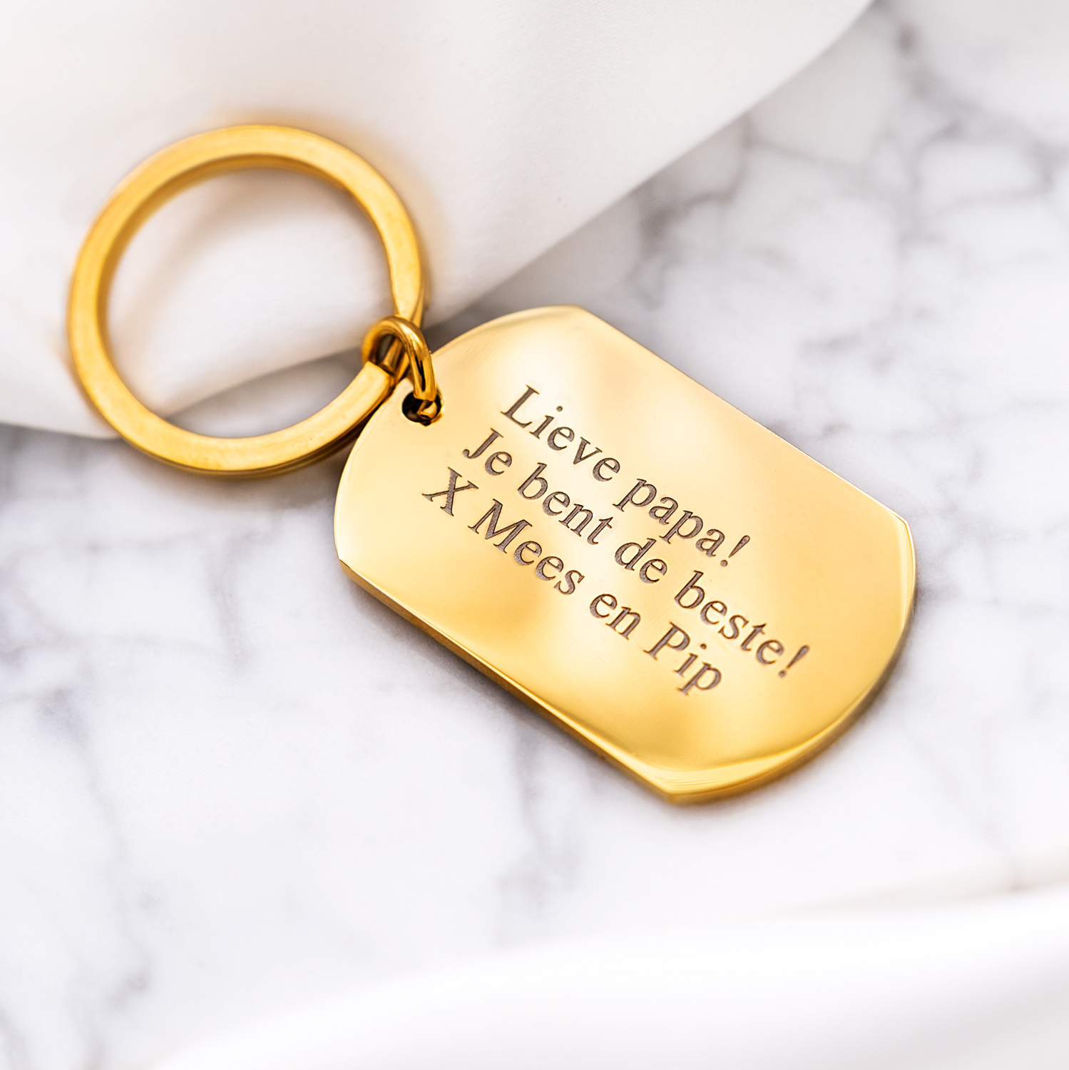Gouden sleutelhanger met tekst op marmeren ondergrond