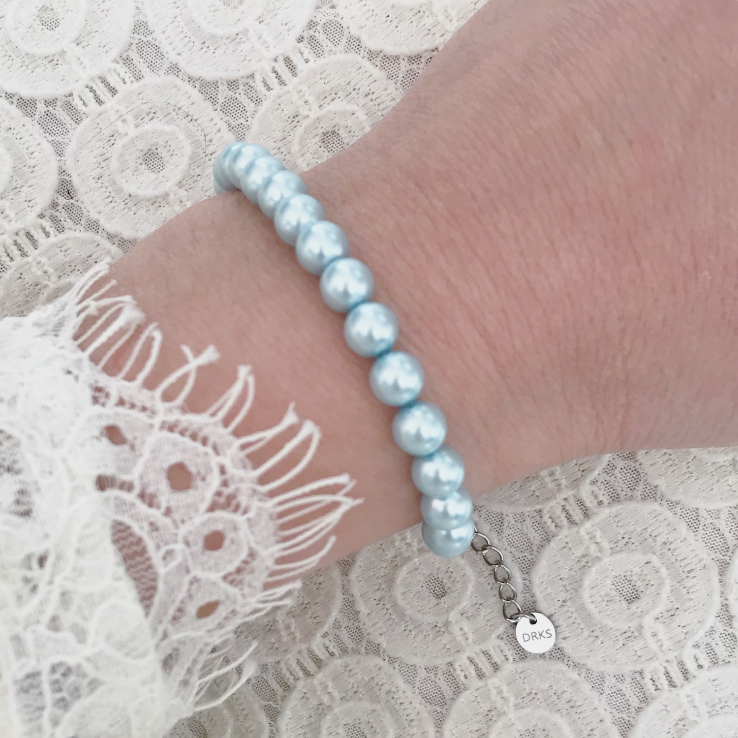 Vrouw draagt lichtblauwe faux parel armband 