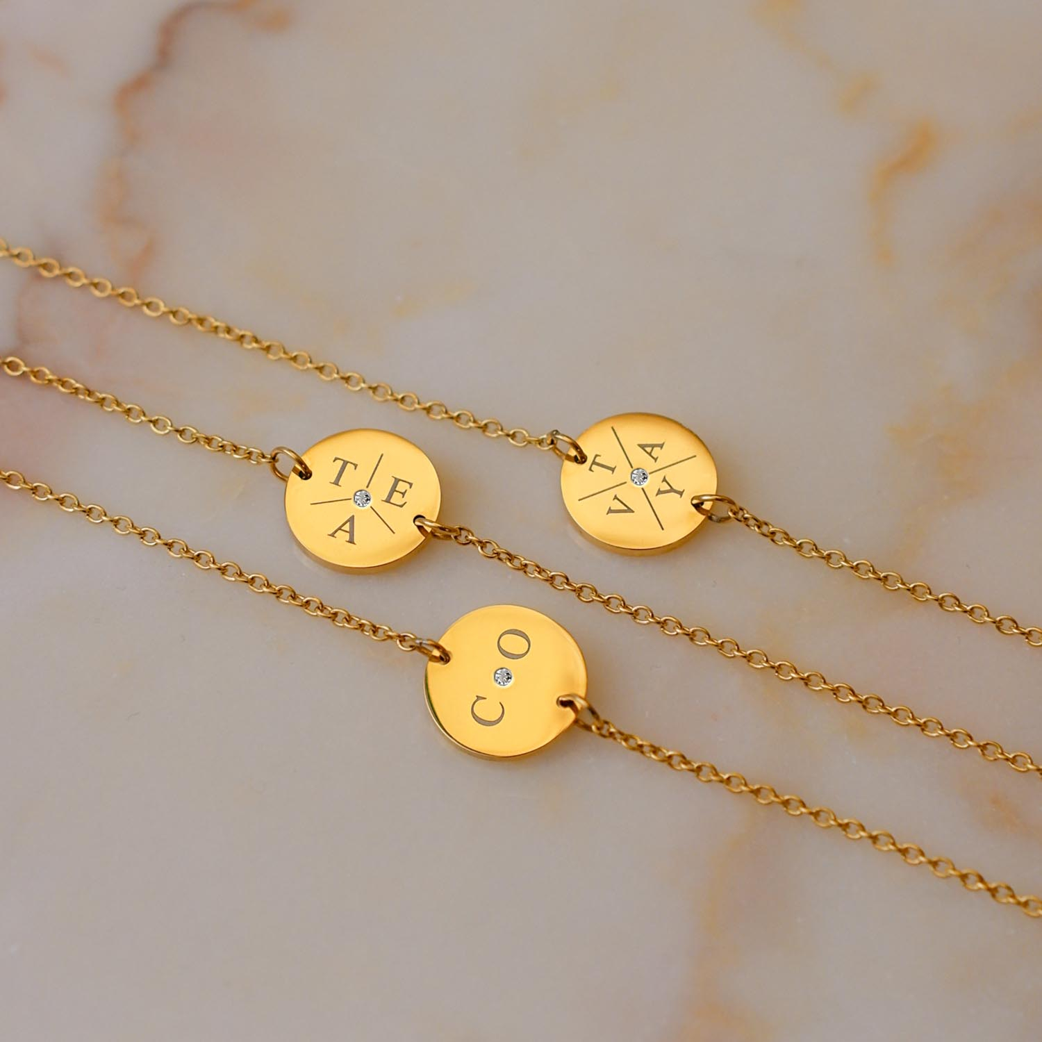 Mix van gouden initial armbanden op marmer