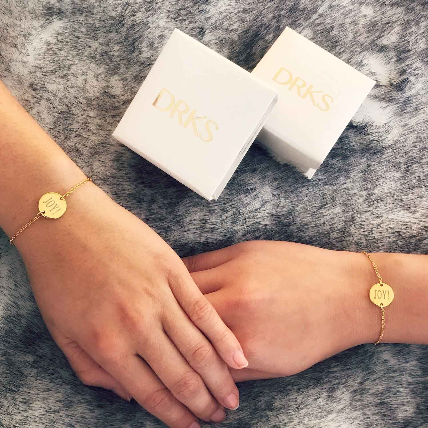 Twee vriendinnen dragen armband met gegraveerde tekst