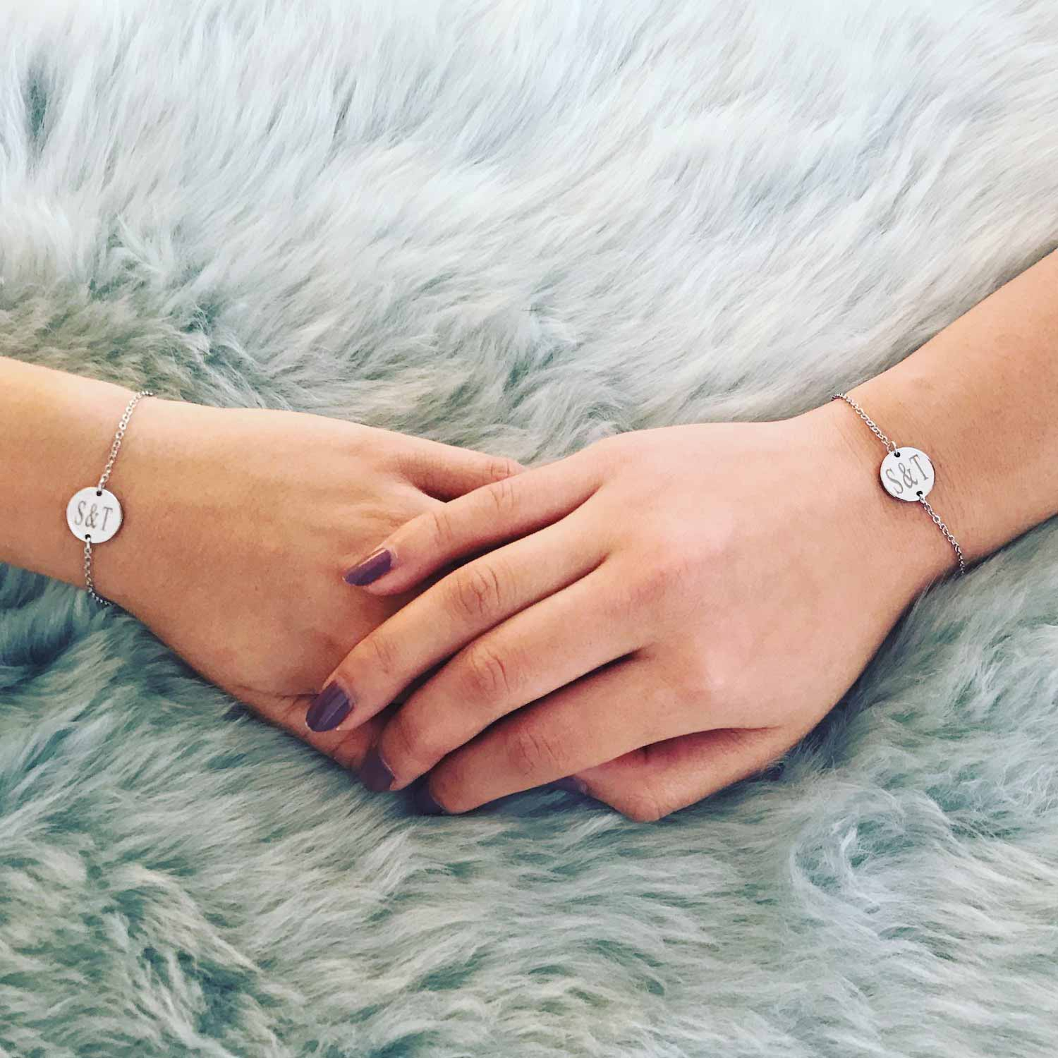Twee vriendinnen dragen een zilveren armband met gegraveerde tekst