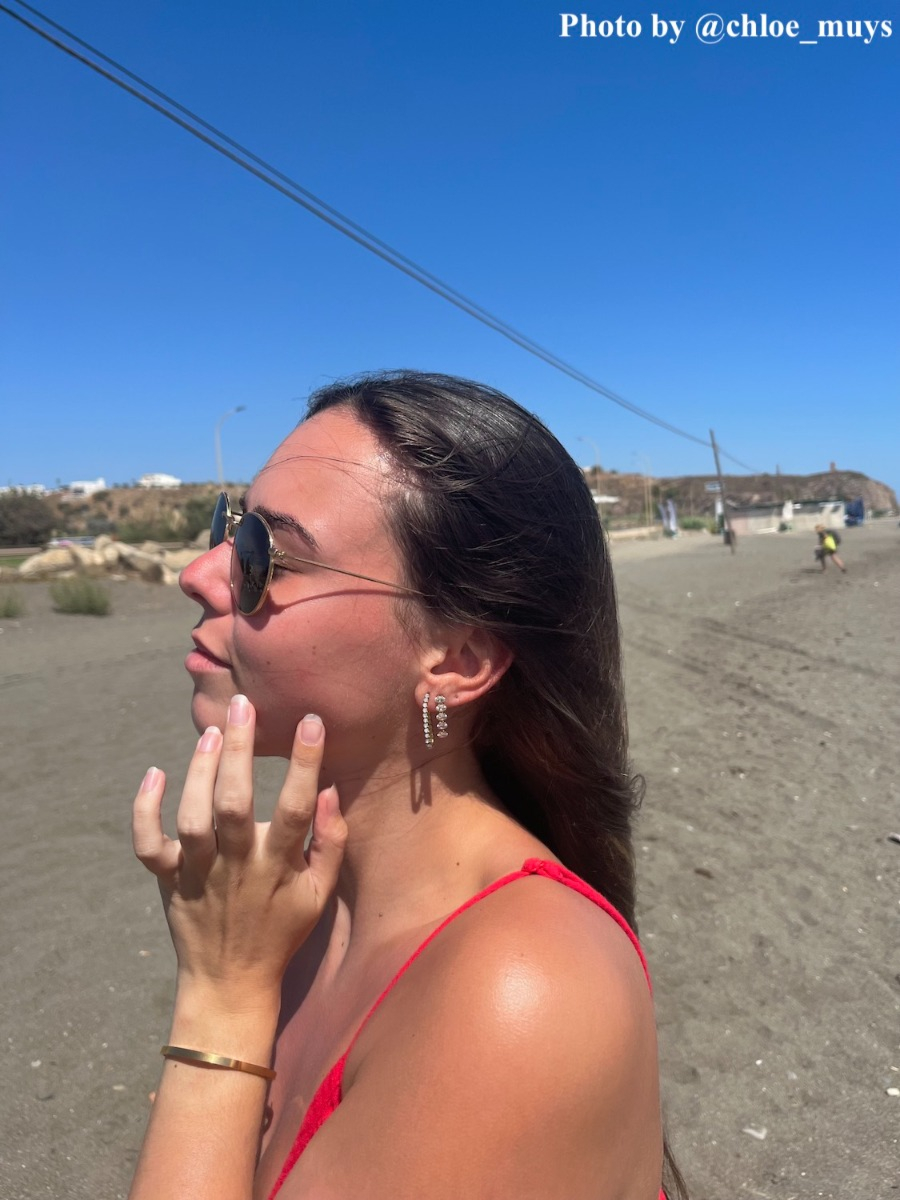 Pols met bangle op het strand en oorbellen