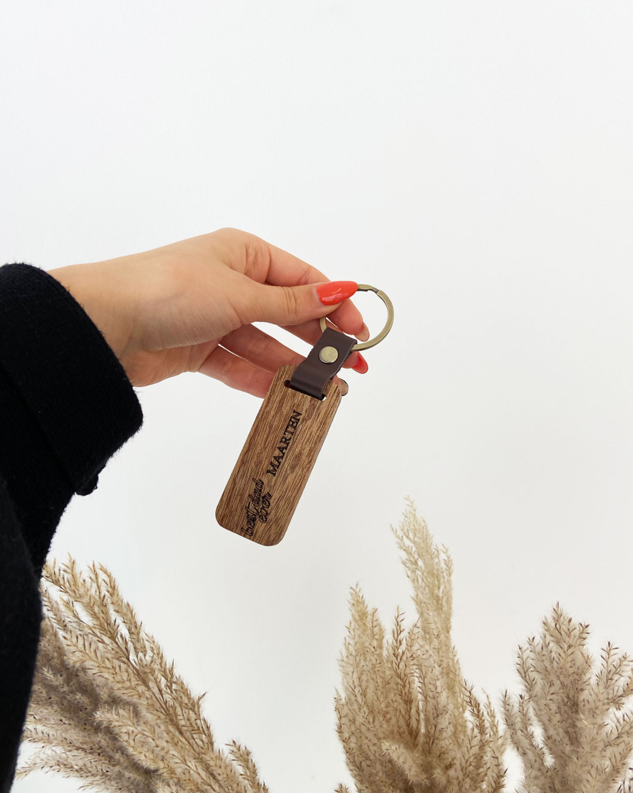 Houten sleutelhanger met naam van vader in de hand