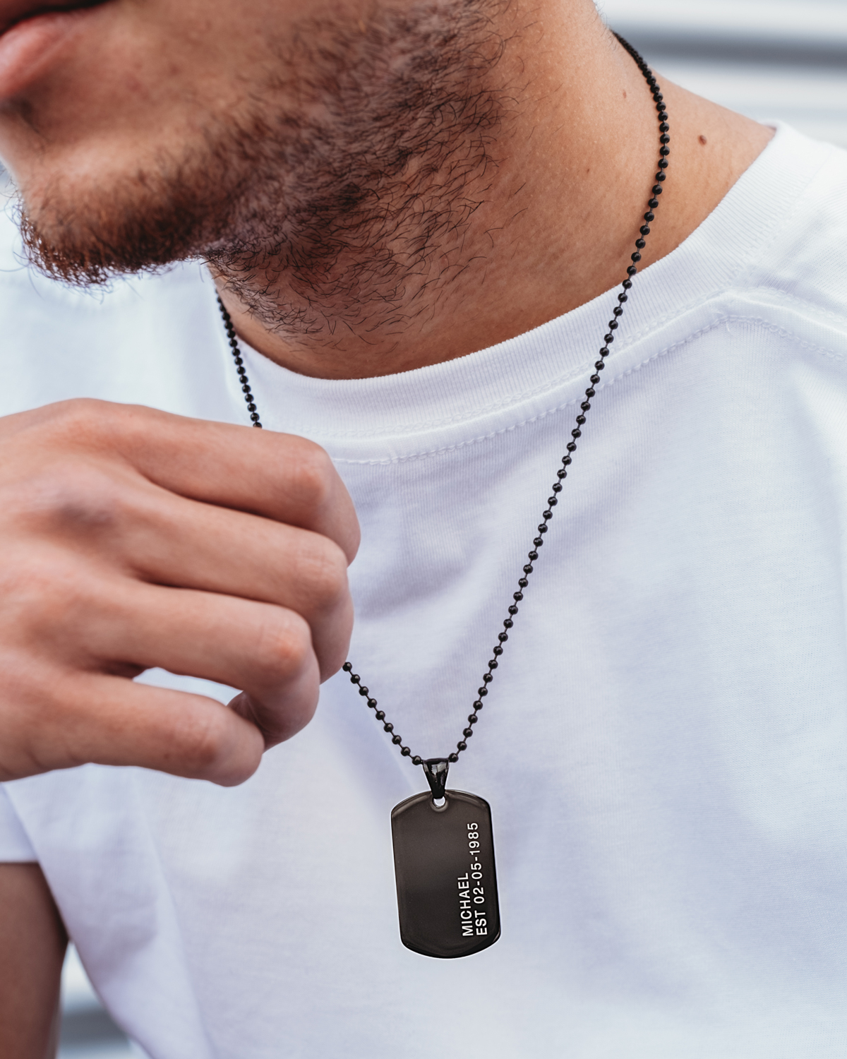 Man draagt zwarte dog tag ketting