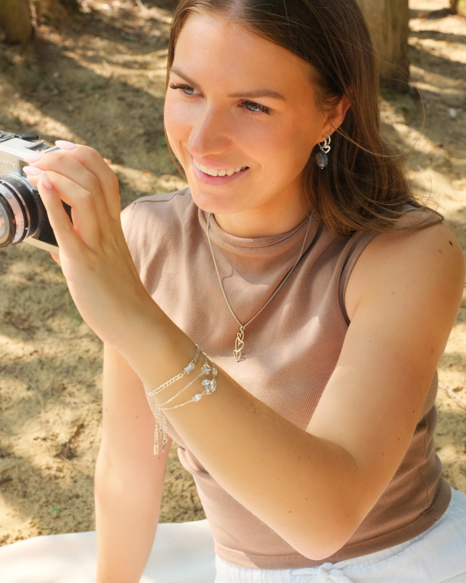 zilveren sieraden met elkaar gecombineerd bij vrouw met camera in haar hand