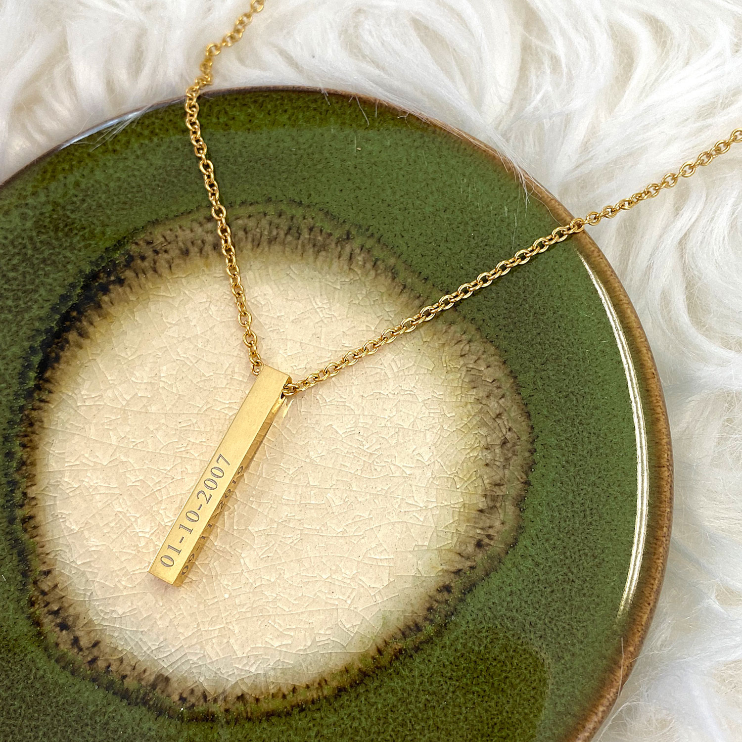 Gouden ketting met gravering op een plaatje met groen