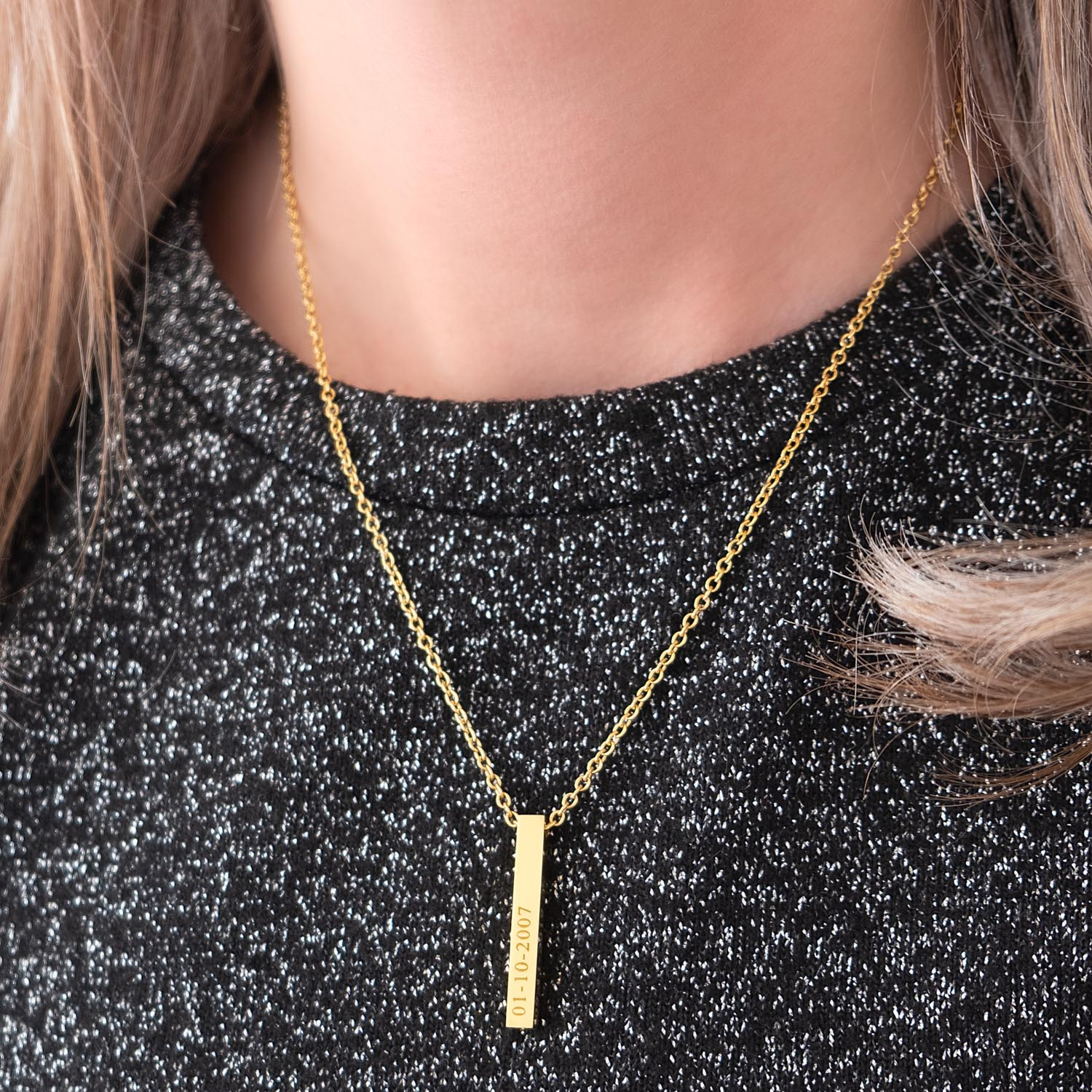 Vrouw draagt een gouden graveerbare ketting om de hals