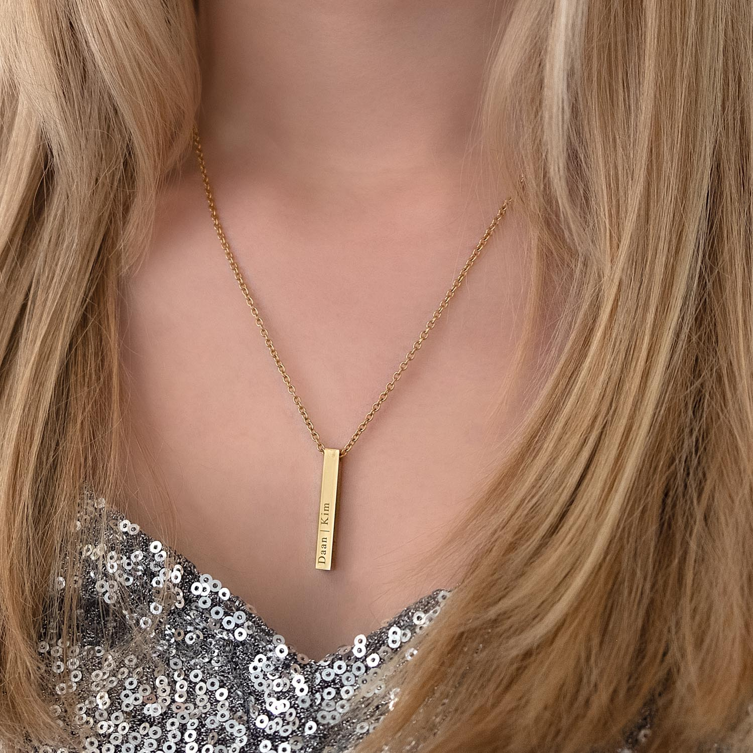 Vrouw draagt graveerbare gouden ketting om de hals bij een zilveren top