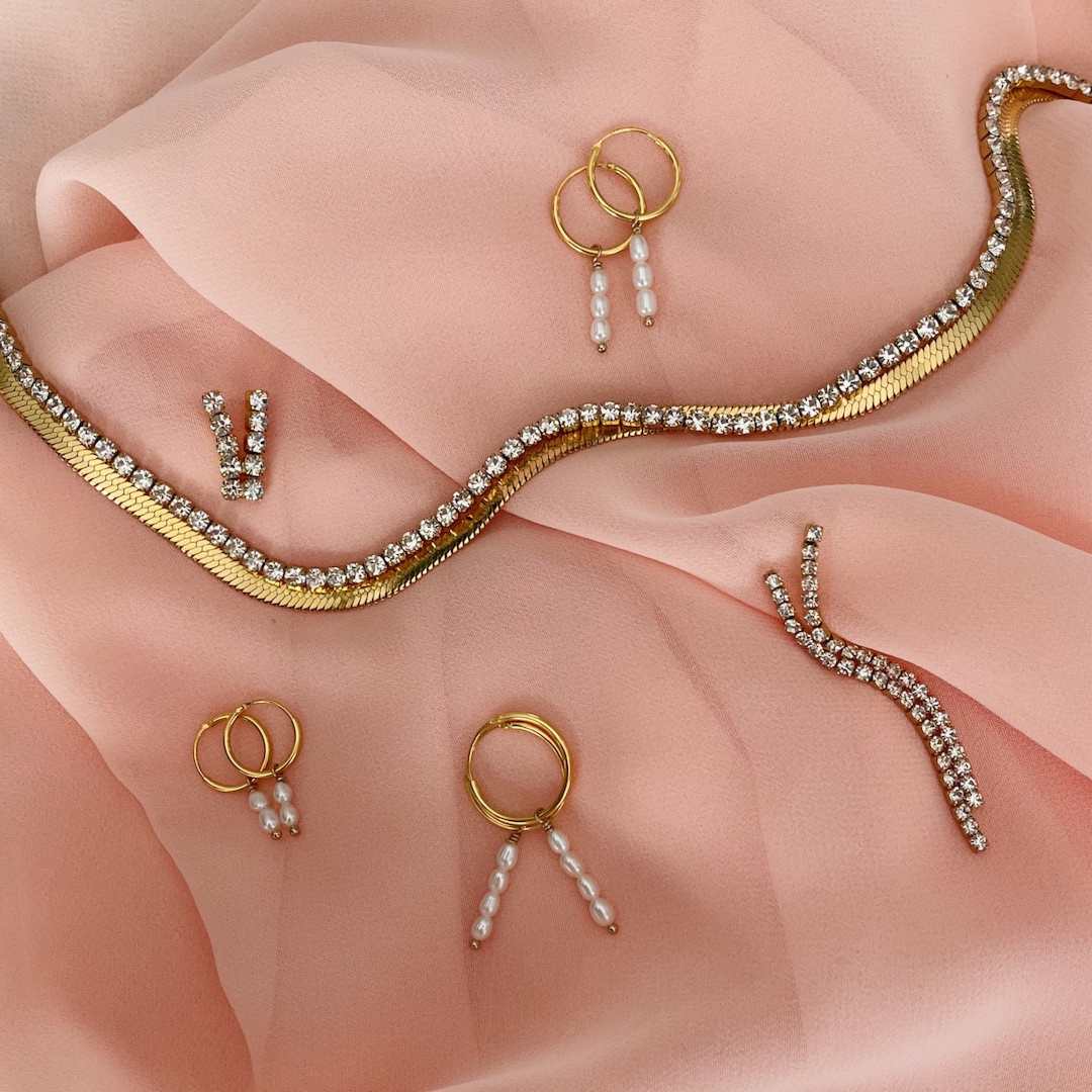 Platte gouden ketting gemixt met andere sieraden