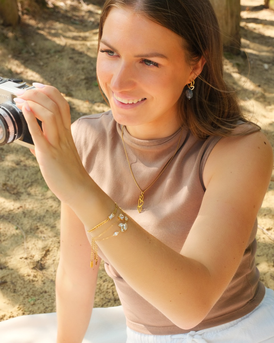 gouden sieraden set bij vrouw met camera in haar hand