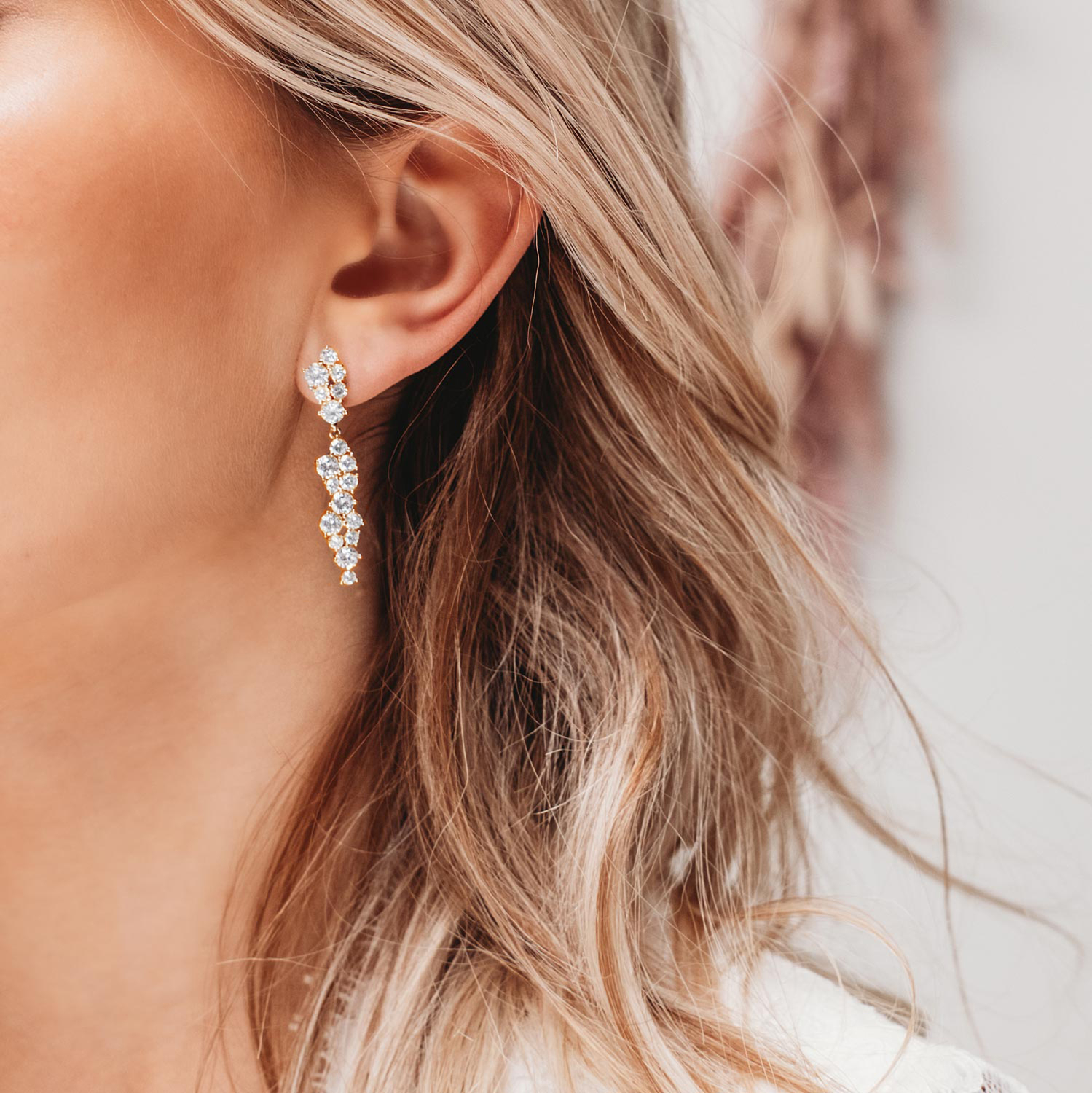 Model draagt gouden bruidsoorbellen met sparkles