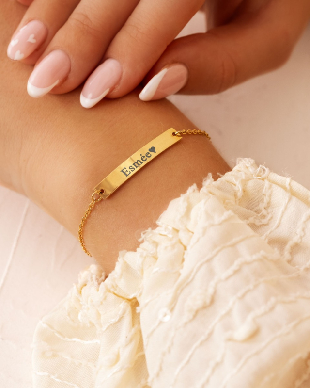 Model draagt gouden bar armband met naam