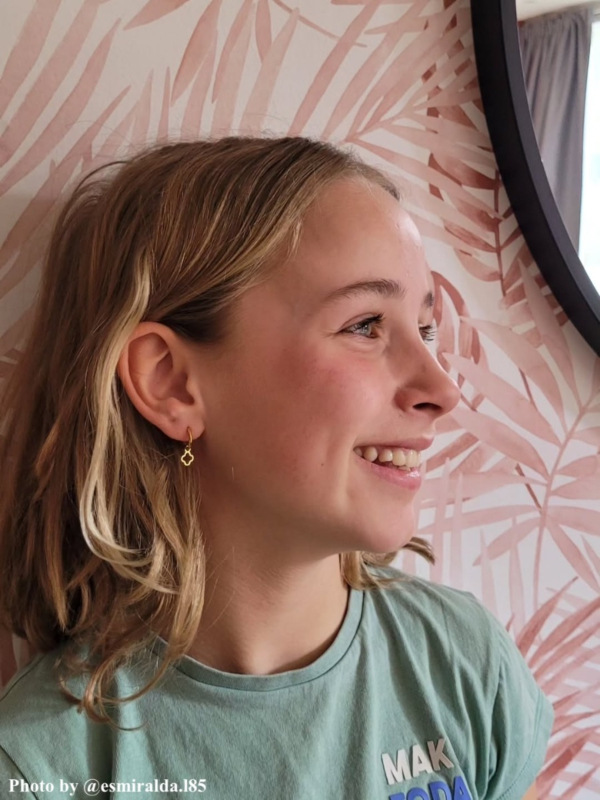 Meisje draagt gouden clover kinderoorbellen