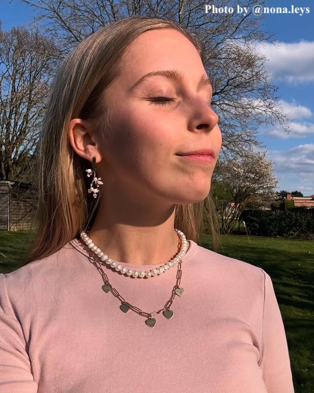 Influencer met parel/gouden oorbellen, parelketting en gouden hartjesketting