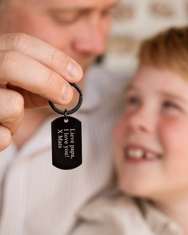 vader en zoon met zwarte sleutelhanger met tekst