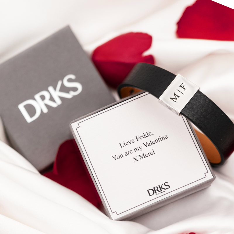 Zwart heren armband met initials bij een sierandendoosje met rozenblaadjes